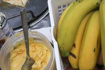Bright yellow ripe bananas in white basket, ready for healthy snack. spoon sits in creamy golden dessert, offering delicious and delightful treat, complementing fresh, sweet fruit