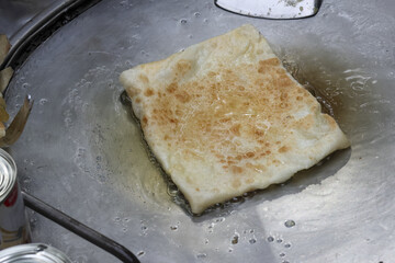 Delicious traditional roti flatbread cooks hot griddle, frying to golden brown perfection. Savory streetfood snack offers an appetizing meal, prepared fresh for breakfast, lunch, or dinner