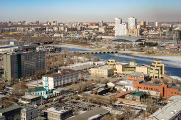 Fototapeta premium Panoramic view from above of the city of Chelyabinsk in Russia Many high-rise buildings of various types are visible, the sky is blue and clear, the weather is cold The Miass River is also visible.