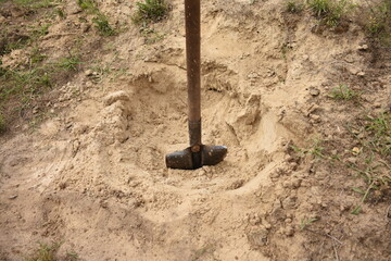 A metal shovel stuck in a pile of sand outdoors. Concept of construction, hard work, building materials, and manual labor. © Anastasiia Harbar