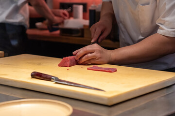 Chef slicing fresh fish on wooden cutting board in professional kitchen