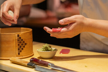 Sushi chef preparing fresh fish with wasabi on wooden countertop