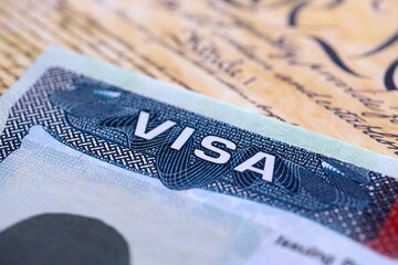Close-up view of a us visa stamped on a passport page with US Constitution background. Travel and immigration concept