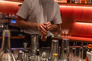Bartender mixing cocktails at bar with various tools and glassware