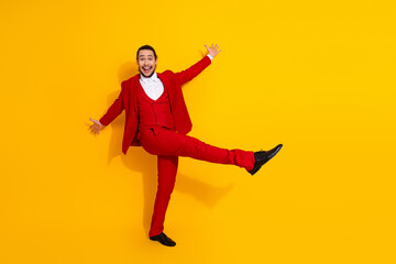 Energetic man in red suit jumps with joy against bright yellow background creating bold fashionable vibe for advertising and lifestyle use