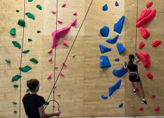 Teenage girl at indoor climbing wall. Kid having fun at bouldering wall. Child learning at climbing class. Sports healthy lifestyle. Youth at climbing summer camp