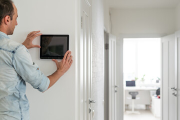 automation, internet of things and technology concept - man looking at tablet pc computer at smart home