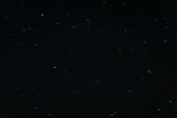 A long-exposure photo of the night sky showing streaks of stars forming short trails, creating a mesmerizing cosmic pattern in deep darkness.
