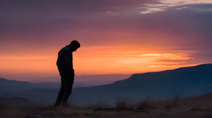 Man silhouette standing alone contemplating sunset mountains
