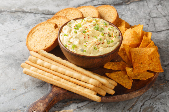 Homemade Deviled Egg Dip sauce with chips, breadsticks and biscuit close-up in a plate on the table. Horizontal