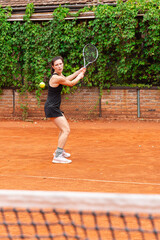 Woman hitting tennis ball on clay court. The photo conveys concentration, movement, and the dynamic balance between power and control in sport.