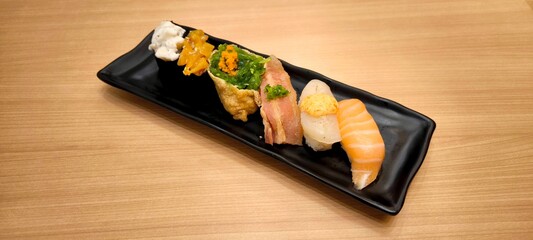 Sushi on a black plate on a wooden table