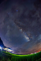 peaceful rural landscape of Milky Way and stars shine over terraced green rice fields at night in cloudy sky after raining in Pa Pong Piang, Chiang mai	