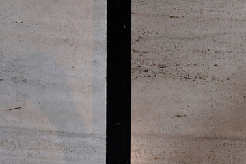Close-up detail of a porous beige stone floor or step with a vertical black anti-slip stripe....