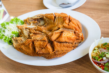 Deep-fried sea bass with fish sauce is popular dish. Deepfried sea bass with fish sauce served with mellow dipping sauce with sliced ​​mango to add flavor and fresh vegetables arranged in white plate