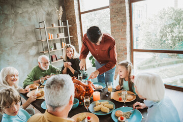 Fun family feast at home joyful gathering around a big turkey as generations come together for...