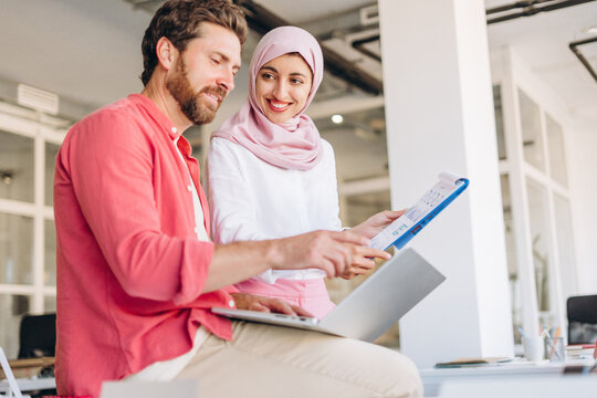 Diverse business colleagues collaborating on laptop and report