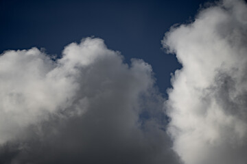 Large cumulus and stratocumulus cloud formations against deep blue sky showing atmospheric layering, light diffusion, and natural contrast useful for meteorology, climate visuals, and sky background
