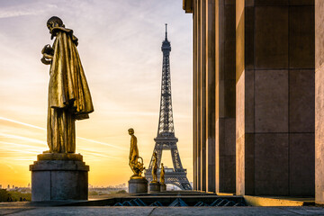 Sunrise on the Eiffel Tower and the golden statues of the Trocadero esplanade along the Chaillot palace in Paris, France.