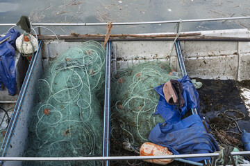 pile of tangled fishing nets and ropes spread across a dock near water in Setubal fishing port, Portugal