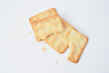Broken crackers with crumbs on white background, top view minimal food photo showing crispy texture, simple composition suitable for snack, bakery, or diet concept.