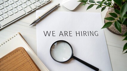 Flat Lay of We Are Hiring Text Under Magnifying Glass on White Desk for Recruitment Concept