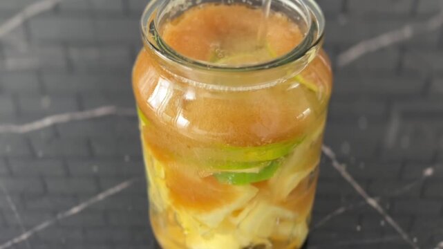 Pour water into a glass bottle to make kombucha. reflection dark background 