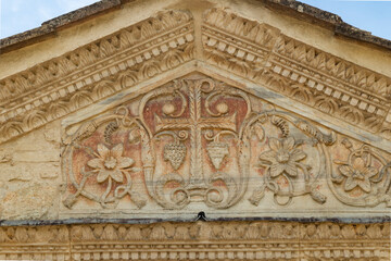 Ancient stone carving depicting cross, grapes, and flowers