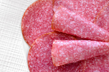 Salami smoked sausage slices in a white plate.