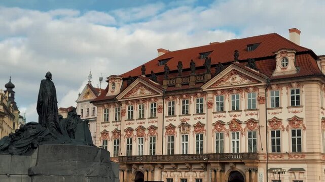 The Jan Hus Memorial statue stands proudly against the ornate Kinsky Palace in Prague's Old Town Square, a symbol of Czech history and religious reform.