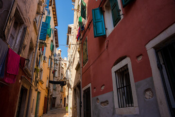 Rovinj, Croatia - August 15, 2025: Narrow Alley in Rovinj – colorful old buildings with open shutters and laundry hanging across a sunlit cobblestone street in the charming old town of Rovinj, Croatia