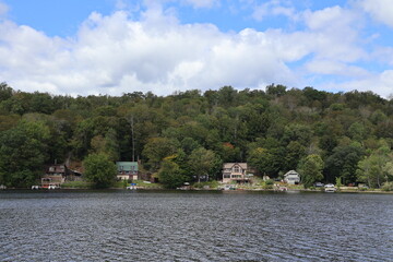 A panoramic view of a row of lake houses tucked into the hillside of a forest.