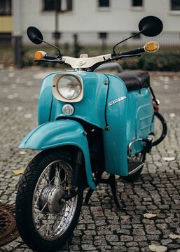 Turquoise Schwalbe scooter parked on cobblestone street