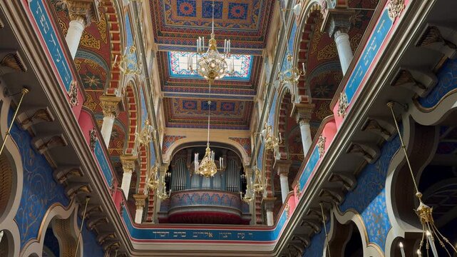 The opulent Neo-Moorish interior of the Spanish Synagogue in Prague, Czech Republic. Exquisite geometric patterns, vibrant colors, and elaborate gold ornamentation showcase 