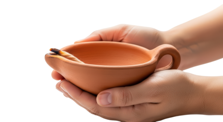 Hands gently cup a traditional earthenware oil lamp symbolizing ancient traditions and sacred light isolated on transparent background