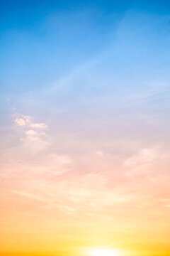 Sunset or sunrise sky with a vibrant gradient of orange, gold, and soft blue. Clear atmosphere with wispy clouds. Peaceful, natural light background. hope, freedom, new day Concepts, Vertical