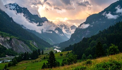 Obraz premium Dramatic sunrise over a stunning mountain valley, with lush green slopes, towering peaks, and a winding river below a cloudy sky