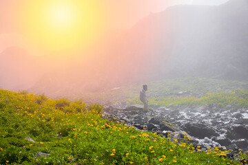 Fototapeta premium Man jumping over river on top of mountain in fog..