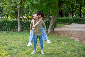Interracial couple enjoying piggyback ride in park