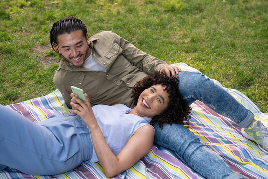 Interracial couple relaxing on picnic blanket in park