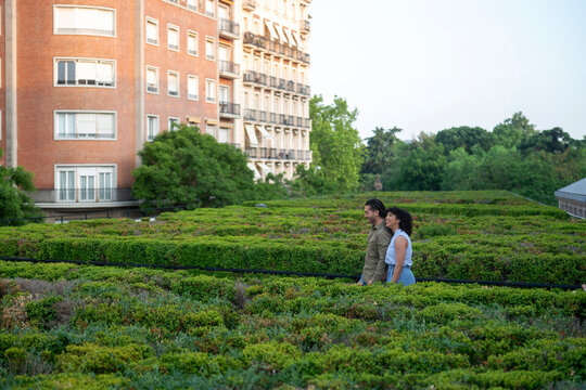 Interracial couple enjoying romantic walk on green rooftop garden