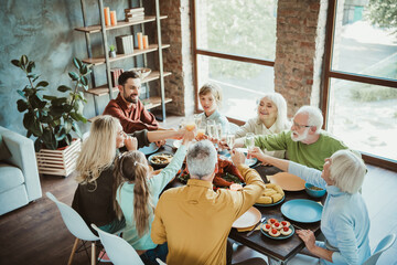 Family gathering around a long table for a joyful thanksgiving feast with turkey and treats in a...