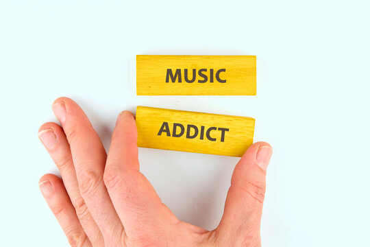 Colorful wooden blocks spell out music addict as a hand reaches out, showcasing the passion for sound. A joyful reminder of the powerful connection to music