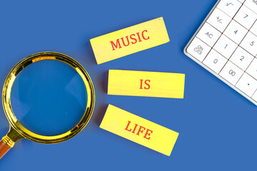 Bright yellow cards say music is life alongside a magnifying glass and calculator on a blue background, highlighting musics role in understanding our world and ourselves