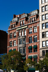 Fototapeta premium A large brick building with a green awning and a clock on the side. The building is surrounded by trees and has a lot of windows