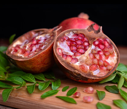 Juicy, fresh, red pomegranate fruit with ripe seeds, cut in half and isolated on a wooden table background for healthy raw food or sweet dessert
