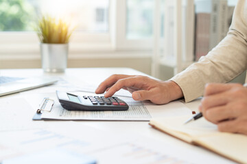 Deduction planning, debt asian accountant hand using calculator to calculating money balance from bill and income, cost budget expenses for pay money form personal individual on table at home.