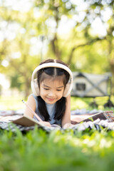 A young child is writing in a notebook in a park.