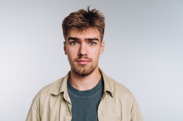 Young man with light brown hair and blue eyes looking directly at the camera in a neutral setting with soft lighting