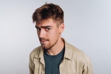 Obraz premium Young man with a playful expression poses against a light background in a casual setting while wearing comfortable clothing